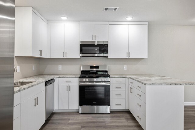 kitchen with recessed lighting, stainless steel appliances, white cabinetry, visible vents, and a peninsula