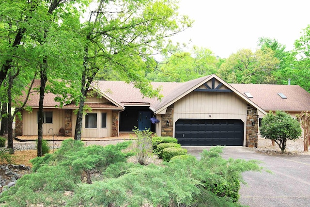ranch-style home featuring an attached garage, roof with shingles, driveway, and stone siding