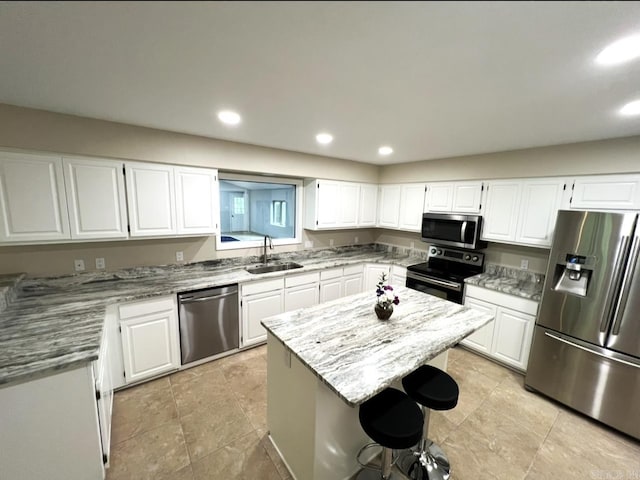 kitchen featuring white cabinetry, appliances with stainless steel finishes, a sink, and light stone counters
