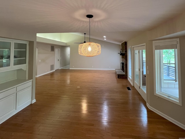 unfurnished dining area with ceiling fan, visible vents, lofted ceiling, and dark wood-type flooring