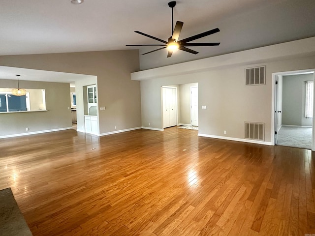 unfurnished living room with visible vents, ceiling fan with notable chandelier, wood finished floors, and high vaulted ceiling