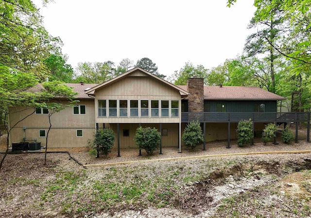 rear view of house with central AC unit and a chimney