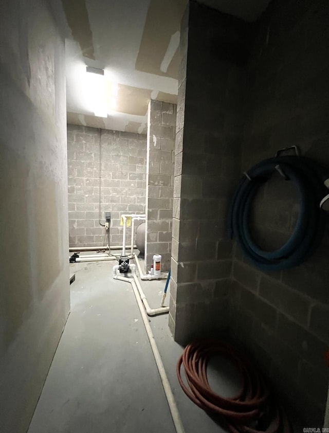 bathroom featuring concrete flooring, toilet, and concrete block wall