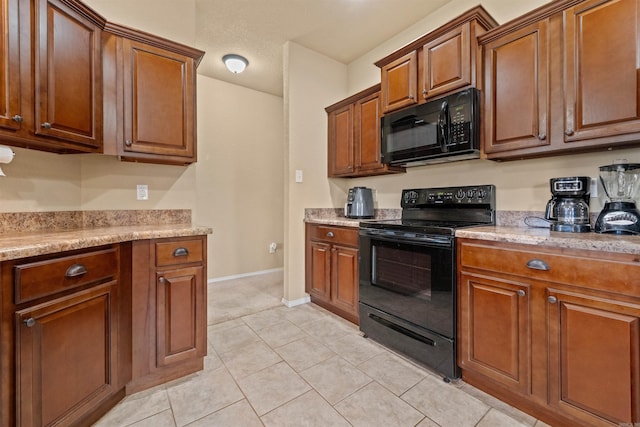 kitchen featuring black appliances, light tile patterned floors, brown cabinetry, and baseboards