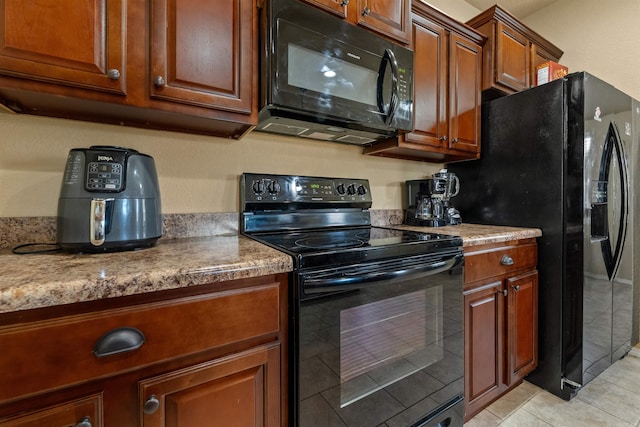 kitchen featuring black appliances, light tile patterned flooring, and brown cabinetry
