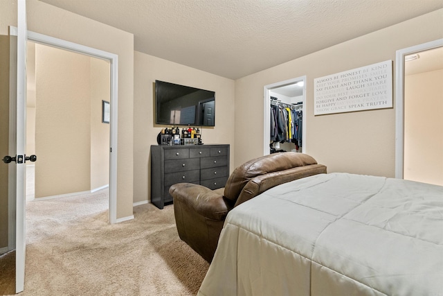 carpeted bedroom with a closet, baseboards, and a walk in closet