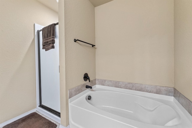 full bath with a textured wall and a bath