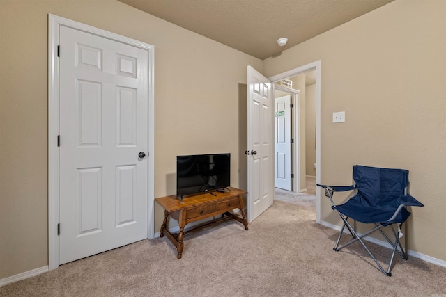 living area featuring light colored carpet and baseboards