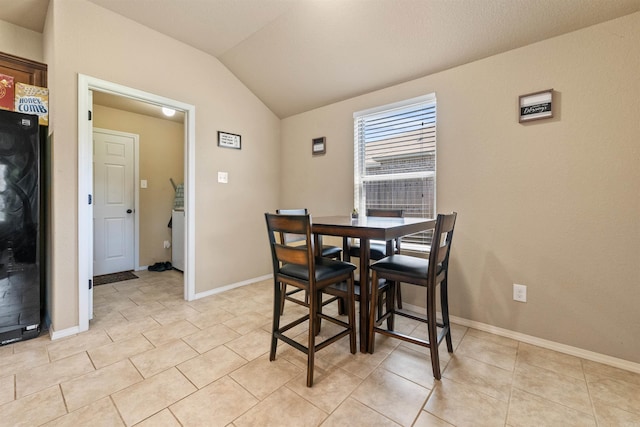 dining area featuring baseboards, light tile patterned floors, and vaulted ceiling