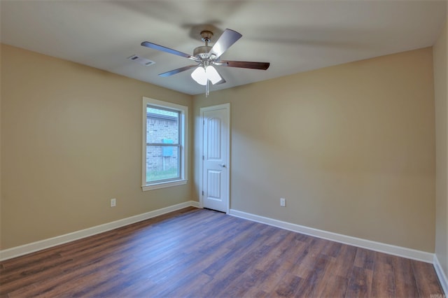 empty room with visible vents, dark wood-style flooring, ceiling fan, and baseboards