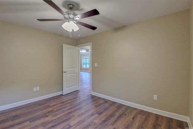 unfurnished room featuring dark wood-style flooring, a ceiling fan, and baseboards