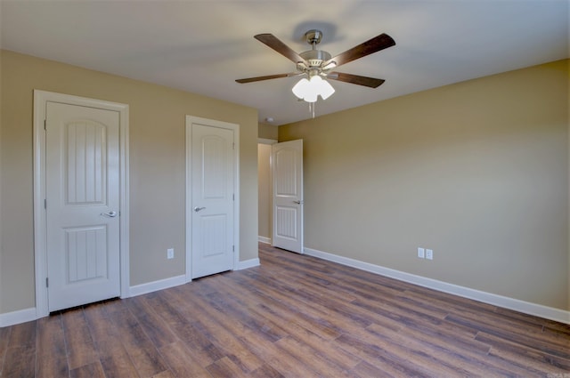 unfurnished bedroom with baseboards and dark wood-type flooring