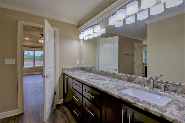 bathroom featuring crown molding, baseboards, wood finished floors, vanity, and a ceiling fan