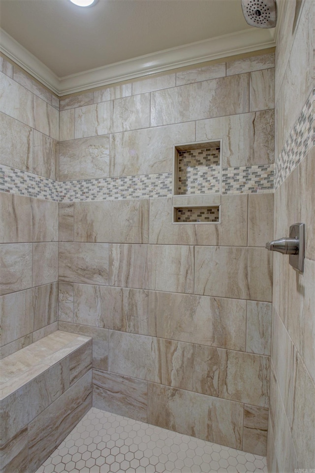 bathroom with ornamental molding and tiled shower