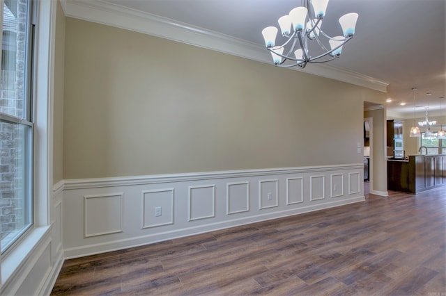 unfurnished room with dark wood-type flooring, a chandelier, ornamental molding, and wainscoting