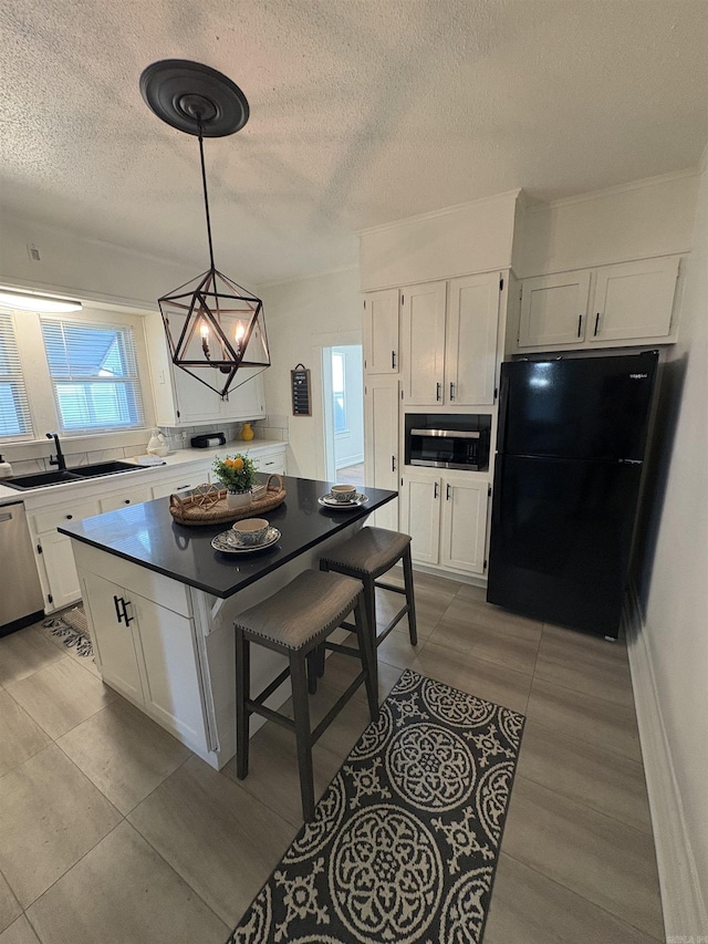 kitchen with a sink, white cabinetry, stainless steel dishwasher, a textured ceiling, and freestanding refrigerator