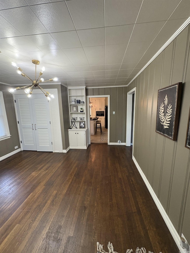 interior space with baseboards, an inviting chandelier, and dark wood-style flooring
