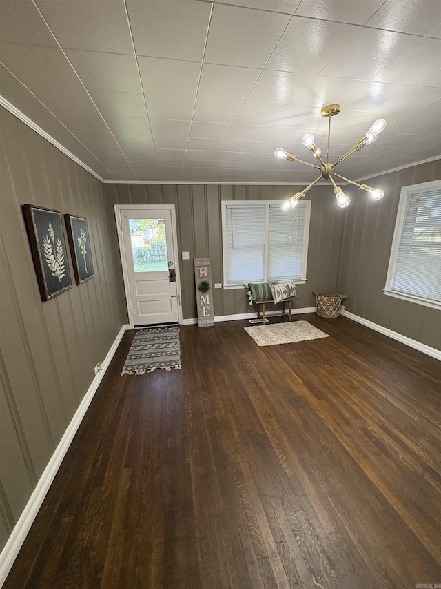unfurnished dining area with baseboards, a notable chandelier, and wood-type flooring