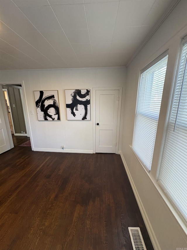 unfurnished dining area with dark wood-type flooring, visible vents, and baseboards