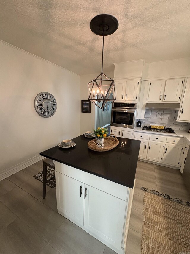 kitchen with white cabinets, stainless steel appliances, a textured ceiling, and a kitchen island