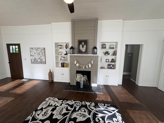 living area with built in shelves, wood finished floors, and baseboards