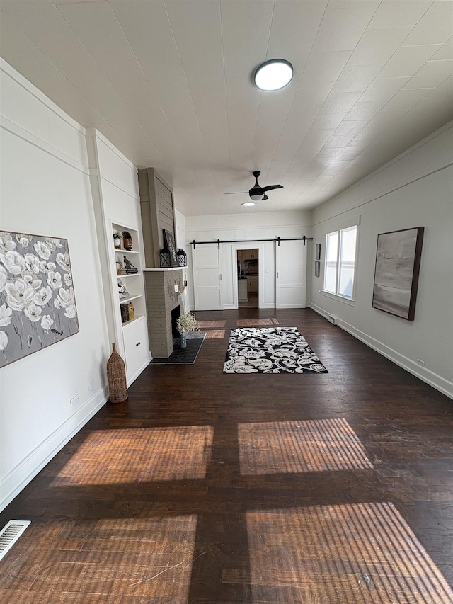 living room featuring a barn door, ceiling fan, visible vents, baseboards, and hardwood / wood-style floors