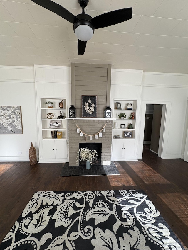 living room with a brick fireplace, wood finished floors, baseboards, and built in shelves