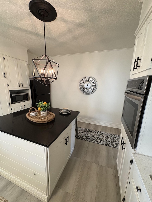 kitchen with a textured ceiling, white cabinets, a chandelier, stainless steel appliances, and wood finished floors