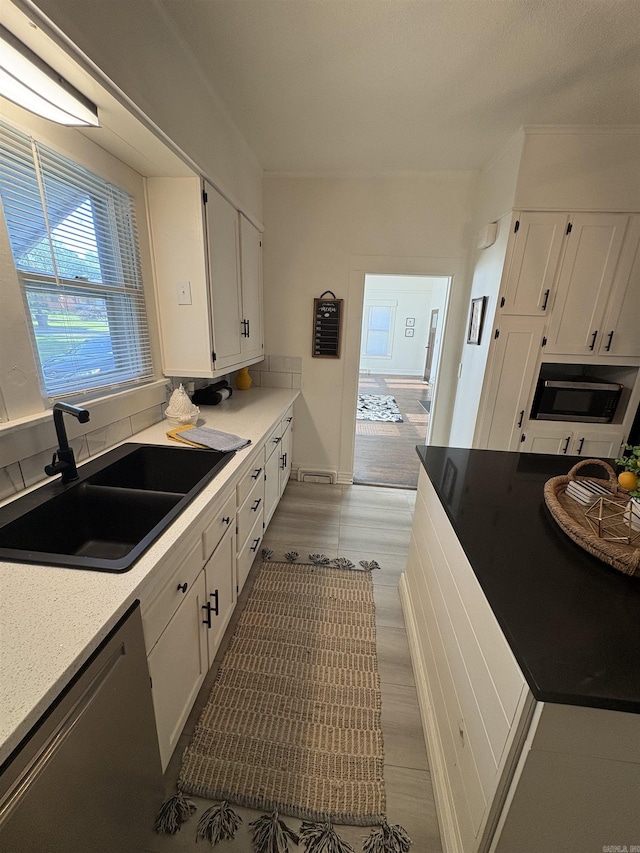 kitchen with a sink, white cabinetry, light countertops, appliances with stainless steel finishes, and wood finished floors