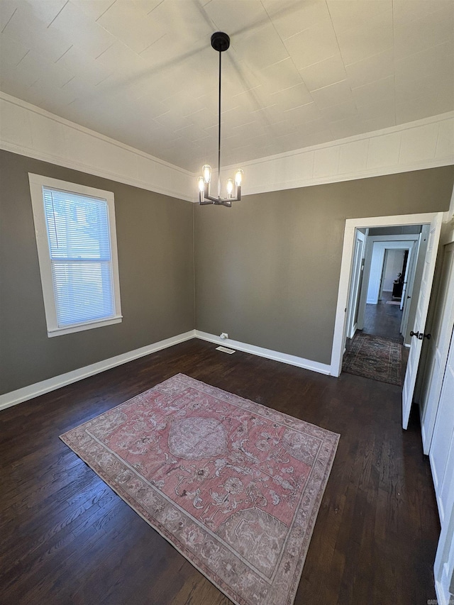unfurnished dining area with a chandelier, dark wood-style floors, and baseboards