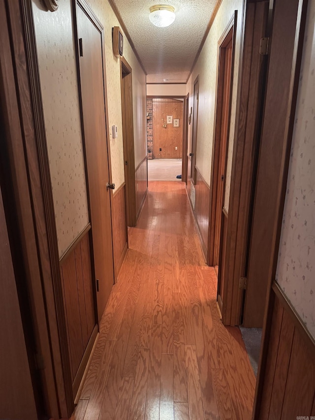 1721 Azalea Hills Rd, White Hall, AR 71602 - corridor featuring light wood-style flooring, a textured ceiling, wallpapered walls, and ornamental molding