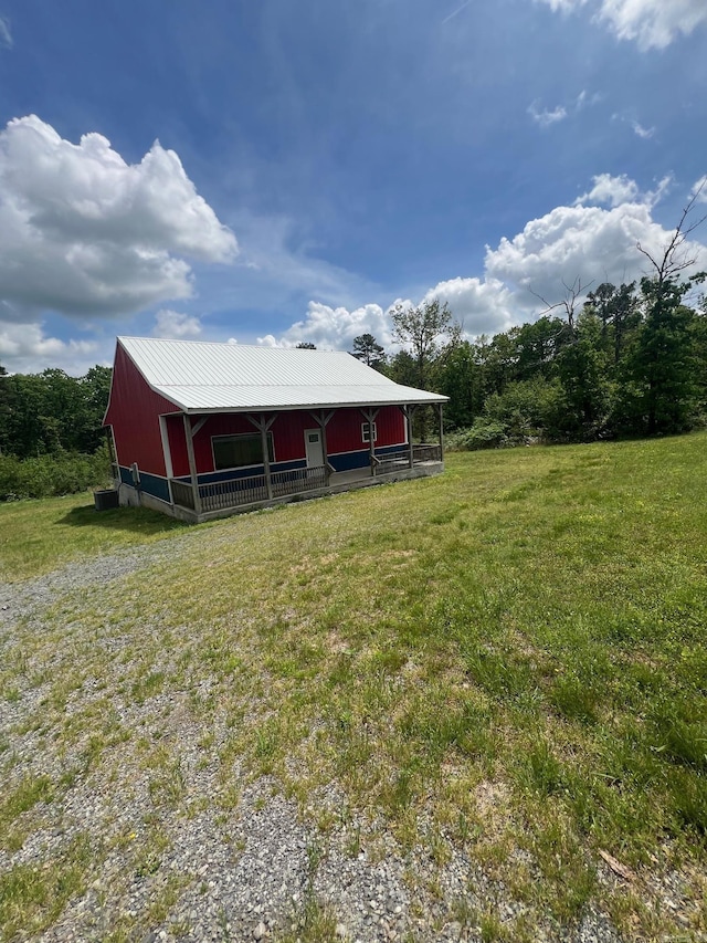 rear view of property featuring a yard and metal roof