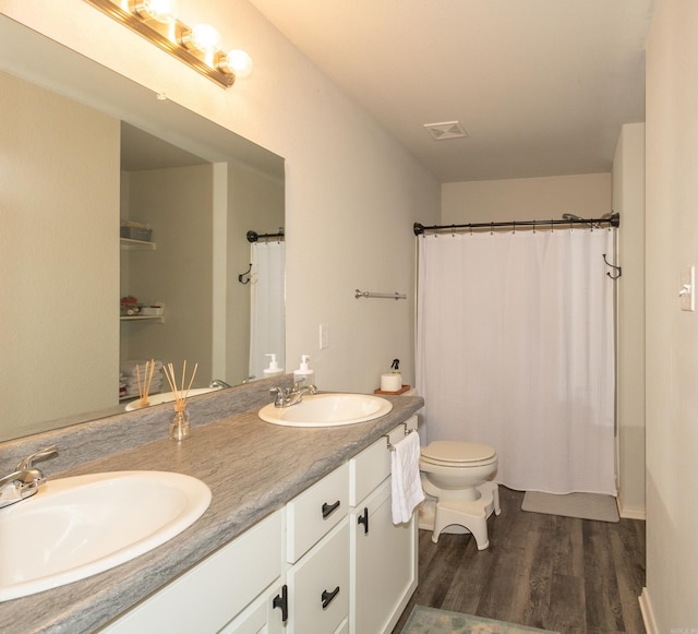 full bath with toilet, a sink, wood finished floors, and visible vents