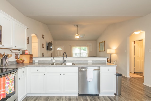 kitchen featuring arched walkways, stainless steel appliances, light wood-style floors, a sink, and a peninsula