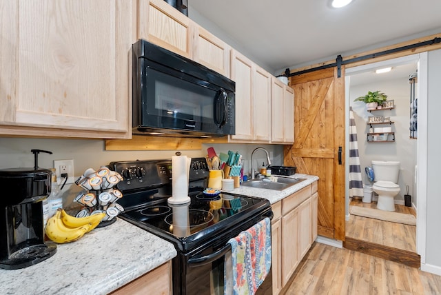 kitchen featuring black appliances, light wood-style floors, light brown cabinetry, and a sink
