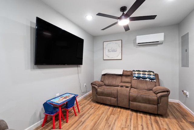 living area featuring light wood-style floors, a wall mounted air conditioner, ceiling fan, electric panel, and baseboards