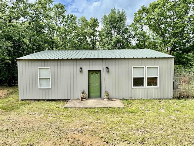 back of house featuring metal roof, a yard, and a patio area