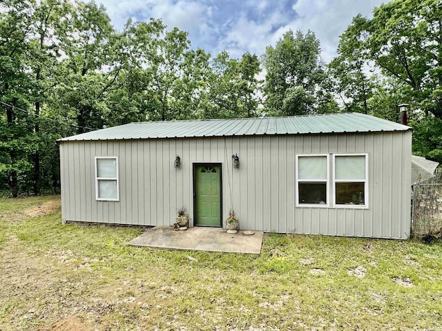 rear view of property featuring metal roof and a yard