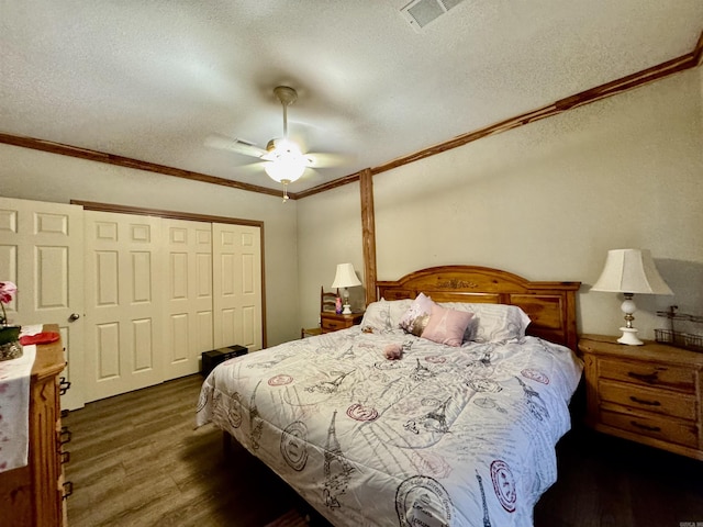 bedroom featuring a textured ceiling, wood finished floors, crown molding, and a closet