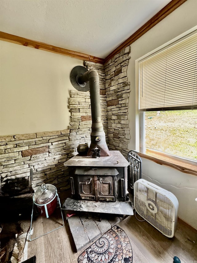 room details featuring a wood stove, a textured ceiling, and wood finished floors