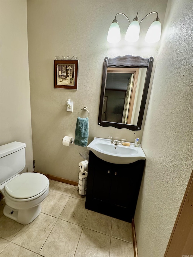 half bathroom with toilet, vanity, tile patterned floors, and baseboards