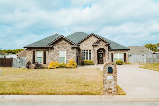 french country style house featuring a gate, a front yard, and a shingled roof