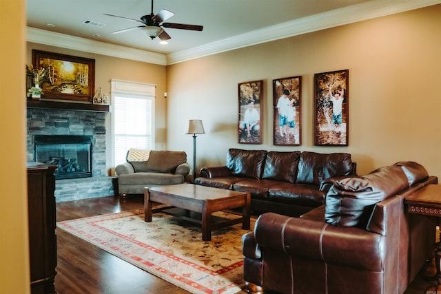living room featuring ceiling fan, a stone fireplace, visible vents, ornamental molding, and wood finished floors