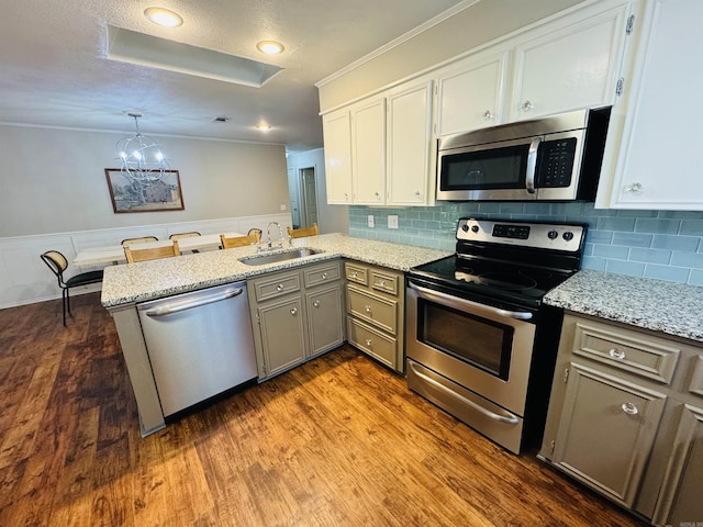 22 Azalea, Magnolia, AR 71753 - kitchen featuring stainless steel appliances, a sink, a notable chandelier, a peninsula, and crown molding