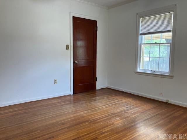unfurnished room featuring wood finished floors, crown molding, and baseboards