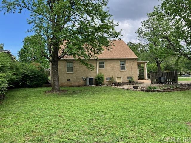 rear view of property featuring central air condition unit, a yard, and brick siding