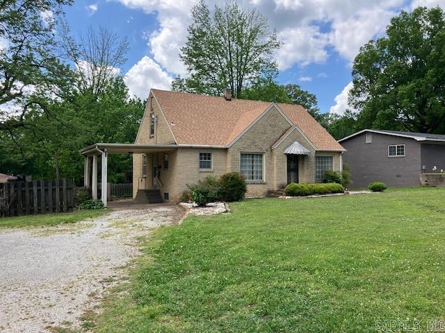 ranch-style home featuring a front yard, driveway, an attached carport, and fence
