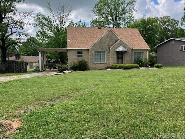 single story home featuring a front yard, dirt driveway, and an attached carport