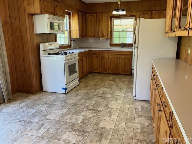 kitchen featuring white appliances, plenty of natural light, brown cabinetry, and light countertops