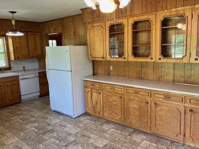 kitchen featuring a sink, light countertops, wooden walls, white appliances, and brown cabinetry
